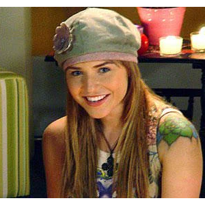 Letícia Colin em 'Floribella': o corte é um médio para longo bem repicado, com camadas graduais e pontas desfiadas para volume. O grande detalhe é o estilo balayage ou luzes de contorno (money piece) em um tom loiro dourado mais claro na frente e nas pontas, contrastando com o fundo castanho. A boina cobre a parte superior