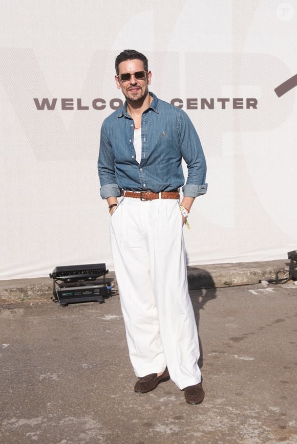 João Vicente de Castro: sua aposta é uma camisaria em jeans de lavagem média com mangas dobradas sobre regata branca, combinada com calça alfaiatada ampla off-white de cintura alta. O toque final vem com cinto trançado de couro marrom, mocassins em camurça escura e óculos escuros retangulares com armação metálica