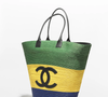 A Chanel apostou no Brasilcore com uma maxibolsa de ráfia trançada em verde, amarelo e azul. O modelo da coleção verão 2026, assinado por Mathieu Blazy, custa aproximadamente R$ 41 mil