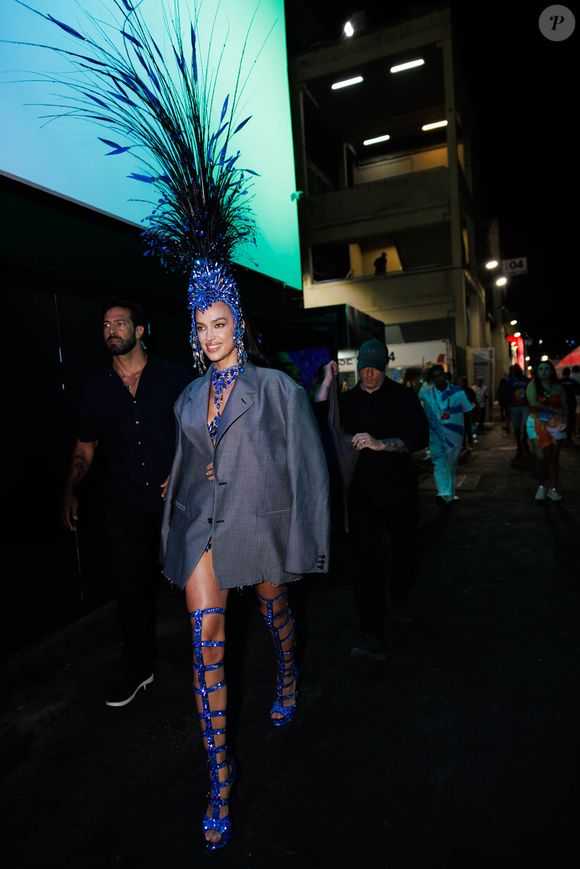 Vestindo um paletó que escondia uma fantasia luxuosa, ela caminhou pelos bastidores com uma imponente peça azul na cabeça, antes de revelar seu traje completo