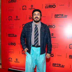 Luis Lobianco: O ator apresenta um look urbano e conceitual composto por jaqueta jeans escura sobre camisa social listrada com gravata tradicional azul e amarela. O visual ganha destaque com uma calça de sarja oversized azul-turquesa, boina preta clássica e sapatos de couro escuros