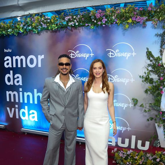 Sérgio Malheiros e Sophia Abrahão: o casal posa em sintonia no tapete vermelho; ele com costume cinza oversized, colete e óculos escuros, e ela com o vestido longo branco minimalista de decote halter e scarpin de bico fino