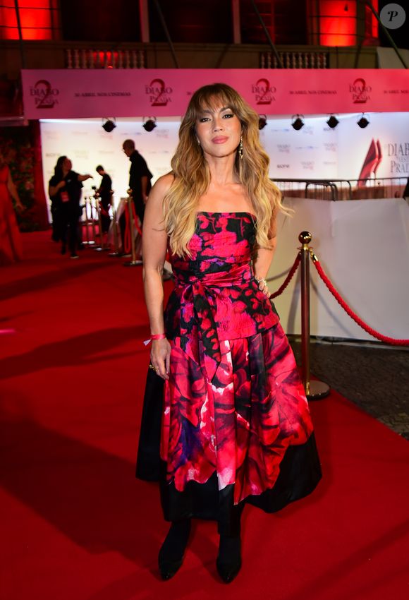 Danni Suzuki: a atriz apostou em um visual de alto impacto visual com um vestido tomara-que-caia de silhueta estruturada. A peça apresenta uma estampa floral maximalista em tons de fúcsia e vermelho sobre um fundo preto, criando um contraste vibrante. O design conta com uma marcação na cintura feita por uma faixa do próprio tecido, que deságua em uma saia de volume controlado com barra assimétrica em preto sólido. Ela finalizou o look com botas de cano curto e bico fino, trazendo um toque moderno à produção clássica