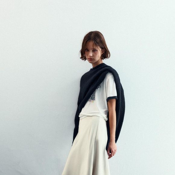 Os vestidos slip dress seguem em alta, principalmente com rendas delicadas e tecidos suaves, e as saias acetinadas entram na mesma tendência romântica. A Zara aposta em um modelo branco com acabamento assimétrico e acetinado que traduz perfeitamente essa estética sofisticada e feminina com renda. Valor: R$ 229,00.
