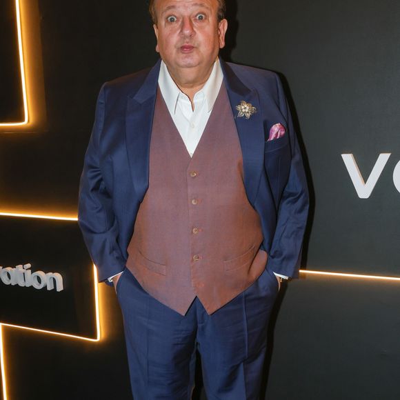 O renomado chef e jurado de TV Érick Jacquin mantém sua assinatura de elegância clássica francesa com um toque de personalidade. Ele comparece ao evento vestindo um terno de três peças composto por um paletó e calça em tecido azul-safira vibrante, contrastado por um colete social abotoado em tom de marrom-rosado acinzentado. Por baixo, uma camisa social branca de colarinho aberto sem gravata mantém o visual imponente porém confortável. Fiel aos detalhes, Jacquin adorna a lapela com um broche floral prateado com pérolas e insere um lenço de bolso rosa-antigo, completando o visual com sapatos sociais oxford pretos de couro legítimo