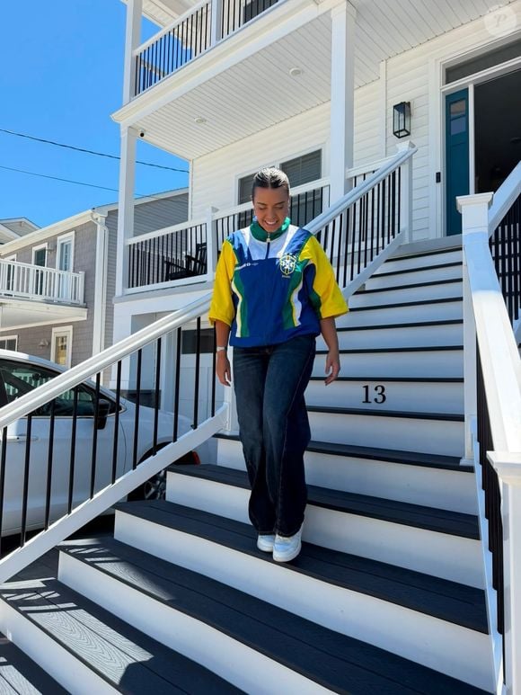 Gabriela Nogueira, esposa de Matheus Cunha, escolheu uma jaqueta 3/4 do Brasil com uma calça wide leg para a estreia do Brasil na Copa do Mundo