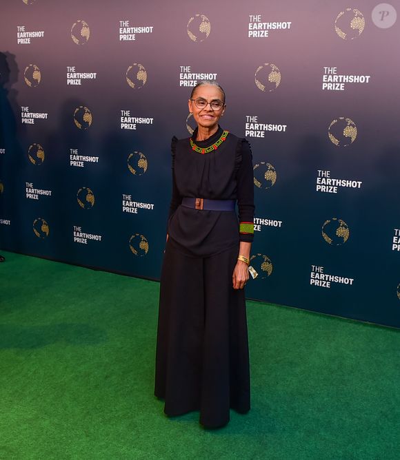 Marina Silva usou um look preto com detalhes verde e laranja no pescoço e no braço esquerdo; o cinto deixou a cintura dela marcada