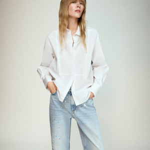 Camisa branca da Zara é levemente alongada, tem gola na lapela, mangas longas, além de fechamento frontal com botões