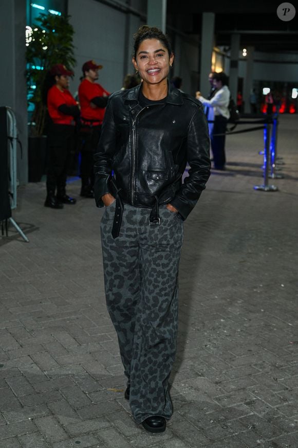 Lucy Alves: veste jaqueta biker de couro preta, camiseta escura, calça ampla em animal print de leopardo em tons cinzas e botas pretas
