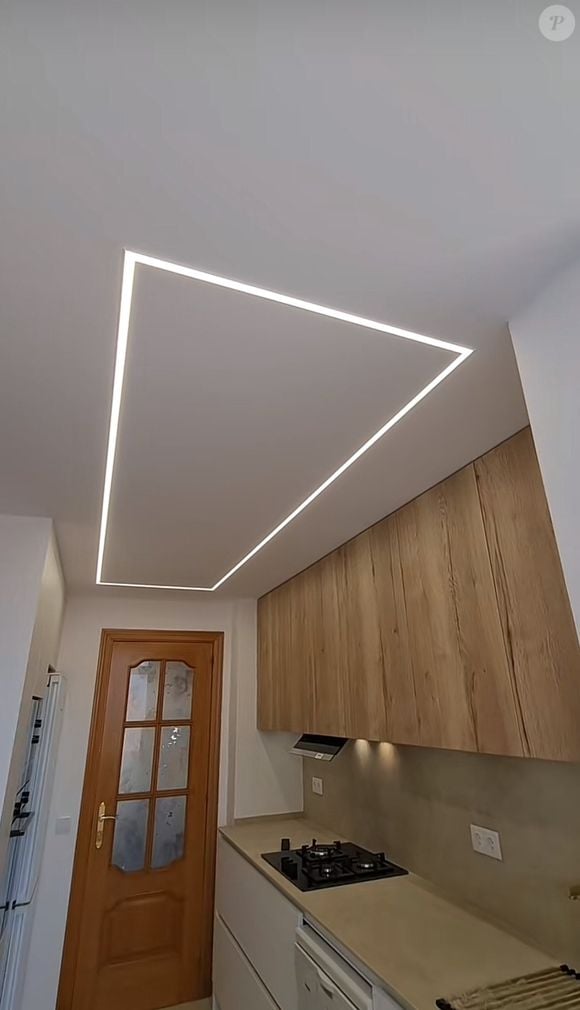 O que realmente proporciona esse efeito incrível  é a iluminação, graças a uma grande luminária retangular de LED no teto da cozinha, que oferece uma  iluminação ambiente diferenciada