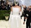 Katy Perry escolheu um visual minimalista e futurista, composto por um vestido tomara-que-caia branco acetinado e luvas longas, tendo como ponto focal uma máscara facial prateada espelhada que cobria completamente seu rosto
