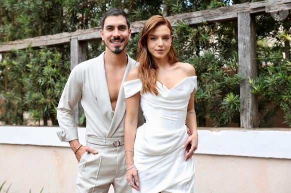 Gabriel David aposta em look com blusa em decote V, enquanto Giovanna Lancellotti usa vestido branco curto de cetim para cerimônia de pre-wedding.