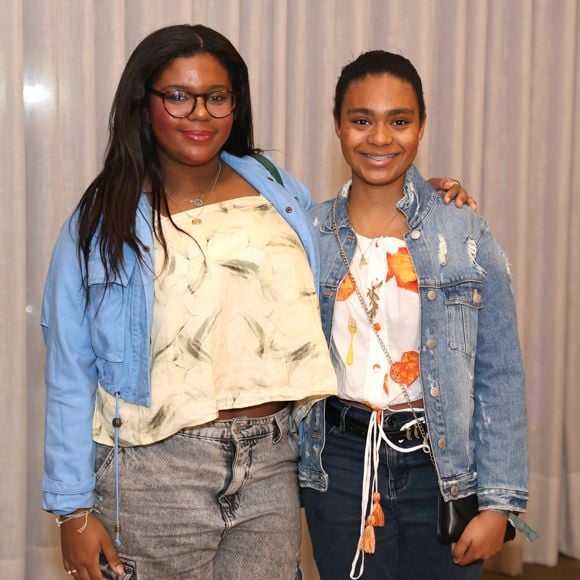 Laura e Maria estavam vestindo calças jeans, blusas estampadas, jaquetas e tênis - um estilo confortável, jovem e descolado para o show