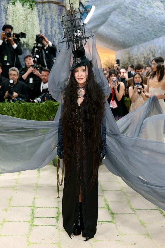 RAINHA DO POP! Madonna compareceu ao Met Gala 2026 com uma verdadeira instalação artística: um barco na cabeça, reinterpretando seu icônico chapéu, e tecidos esvoaçantes que remetiam ao mar. A artista impactou com um visual todo em preto, dramático e conceitual