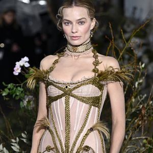 O look de Margot Robbie na première reforçou a narrativa do filme: vestido nude de estética vitoriana, criado por Dilara Findikoglu, em sintonia com a joia histórica escolhida para a ocasião
