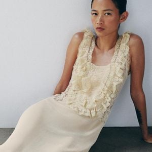A Zara traz uma versão sofisticada da tendência com o Vestido Longo Drapeado em Renda, disponível por R$ 739, unindo fluidez, babados e detalhes rendados