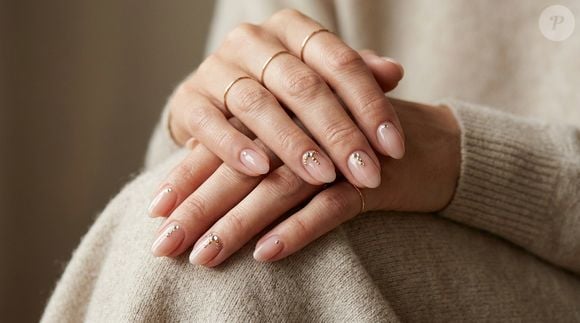 Unhas com joias: As jewelry nails combinam a base nude e translúcida das unhas com efeito sabonete com pequenas pedrarias aplicadas estrategicamente. A proposta acompanha a tendência de incorporar cristais e elementos decorativos à manicure, criando um contraste entre a aparência natural do esmalte e o brilho dos acessórios