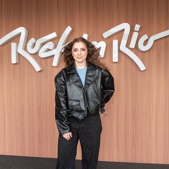 Giana apresenta uma estética rocker urbana e despretensiosa. A cantora veste jaqueta de couro estilo perfecto em modelagem oversized, blusa azul e calça jeans preta ampla com sutis detalhes brilhantes, finalizando com botas de sola tratorada