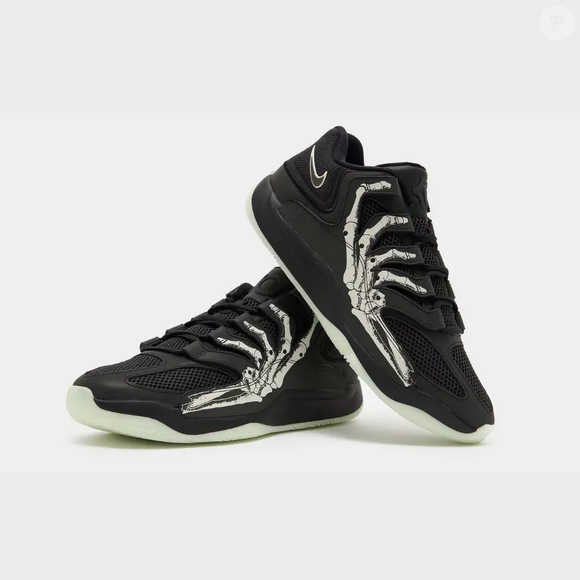 A mão esquelética estampada na lateral é um dos principais destaques do Nike KD 18 'Halloween'. O desenho aparece sobre uma estrutura diferenciada no mediopé, inspirada no Air Terra Humara, reforçando a identidade visual da edição especial