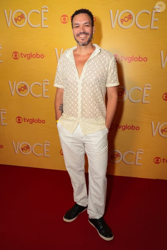 Ator aposta em uma proposta leve e urbana com camisa de tricô rendado em tom off-white e decote V, combinada a uma calça reta branca. O contraste da produção fica por conta dos tênis pretos e do brinco pendente minimalista