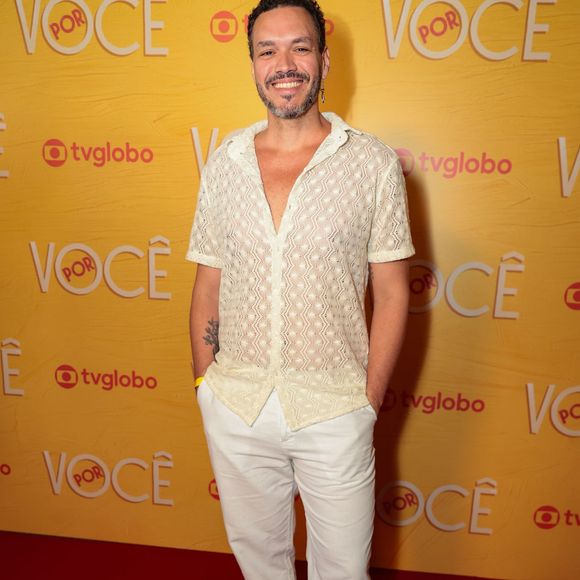 Ator aposta em uma proposta leve e urbana com camisa de tricô rendado em tom off-white e decote V, combinada a uma calça reta branca. O contraste da produção fica por conta dos tênis pretos e do brinco pendente minimalista