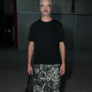 Guilherme Weber apostou em uma produção conceitual ao destacar uma calça de modelagem ampla com estampa gráfica em preto e branco com motivos artísticos. Ele equilibrou a peça chamativa com uma camiseta preta básica de gola careca e mangas curtas. O ator completou o visual com tênis preto estilo All Star, óculos de armação marcante e uma bolsa tira-colo tirada a tiracolo