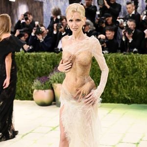 Sabine Getty exibiu um vestido transparente em tom nude com efeito 'molhado' e texturizado, apresentando detalhes surrealistas de mãos esculpidas que parecem envolver seu corpo estrategicamente