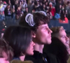 Shawn Mendes optou por uma composição minimalista na plateia, vestindo uma camisa ou jaqueta preta de abotoamento frontal e carregando também sua credencial de acesso, enquanto ostenta as clássicas chuquinhas brancas estilo Xuxa presas ao cabelo cacheado