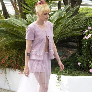 Com styling assinado por Tara Swennen, Stewart usou um look Chanel rosa-claro composto por um cardigã de tweed de manga curta e um short combinando, com uma saia longa rosa transparente por cima
