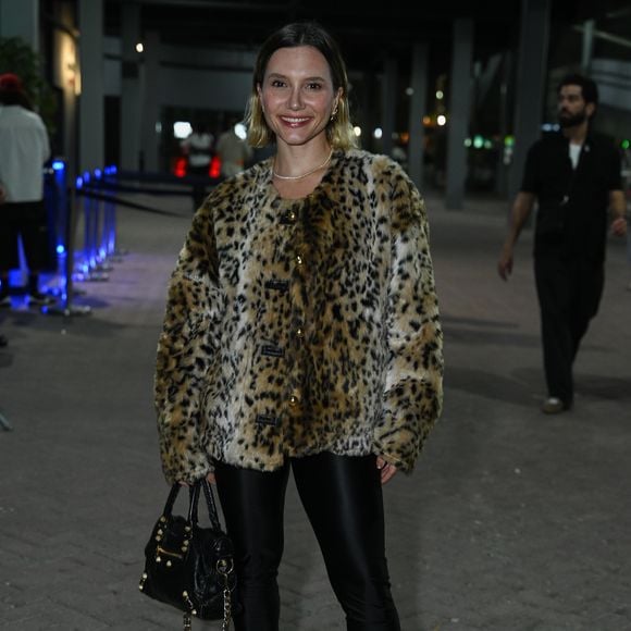 Bianca Comparato: combina um casaco de pele sintética em estampa de oncinha com calça legging preta acetinada, coturnos pretos de salto tratorado e bolsa preta com tachas