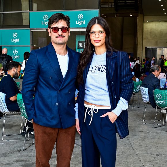 O ator Daniel Rocha veste um blazer transpassado azul-marinho, ajustado ao corpo, que ganha leveza ao ser combinado com uma camiseta branca básica por baixo, deixando o visual menos rígido enquanto Vitória Strada elege calça pantalona azul-marinho fluida mantém a elegância da silhueta, finalizada com maestria por escarpins de bico fino para o Rio2C