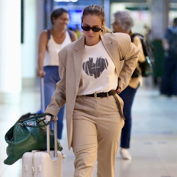 Paolla Oliveira desfilou pelos corredores do aeroporto usando um look composto por maxi blazer com ombreiras e calça social, além de uma camiseta de meia manga branca.