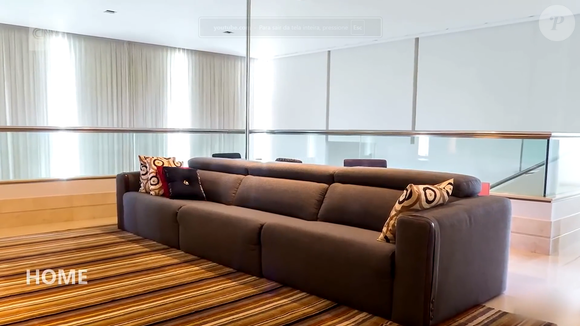Sala de estar com sofá e televisão faz parte dos ambientes da residência de dois andares. Segundo a descrição do imóvel, a mansão também possui salas de estar e jantar, além de escritório e home theater