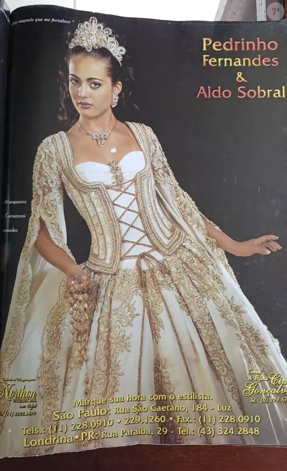 8. Vestido dourado

Um verdadeiro momento da moda nupcial do início dos anos 2000. O vestido traz um corpete estruturado em tom off-white, com aplicações em dourado que seguem um desenho rococó luxuoso. A parte central é marcada por um trançado de fitas douradas, que alonga a silhueta e reforça a ideia de cintura marcada. As mangas são estilo cape, totalmente rendadas e bordadas com arabescos dourados, transmitindo uma imponência quase real. 

A saia volumosa ganha destaque com bordados em arabescos florais, criando um contraste entre opulência e delicadeza. O look é finalizado com uma tiara robusta cravejada de pedrarias, brincos e colar maximalistas, o auge da estética rainha barroca que dominava os editoriais de noiva da época.
