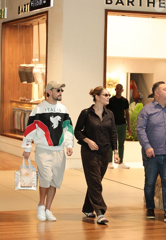 Entre sacolas e óculos escuros, Arrascaeta e Camila Bastiani tentam passar despercebidos em shopping carioca após um dos anos mais vitoriosos da carreira do jogador