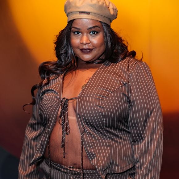 A cantora MC Carol esbanjou atitude com um conjunto de alfaiataria desconstruída em risca-de-giz marrom. O look é composto por uma calça de corte reto e um blazer cropped amarrado frontalmente por laços finos, deixando o abdômen à mostra em uma proposta audaciosa e moderna