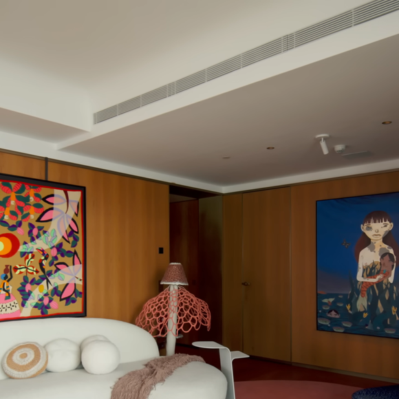 A sala do novo apartamento de Isabeli Fontana e Di Ferrero reúne arte, memória afetiva e personalidade, com sofá da Artefacto voltado para a janela, tapeçaria de Kennedy Bahia e instrumentos musicais, incluindo um violão de 1978 comprado com o segundo salário do pai do cantor