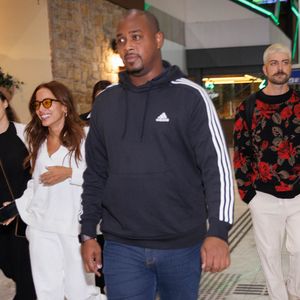 Anitta no aeroporto com fãs e o empresário Ian Bortolanza