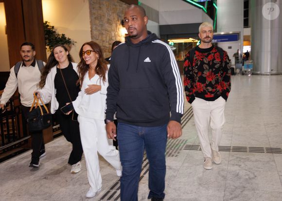 Anitta no aeroporto com fãs e o empresário Ian Bortolanza