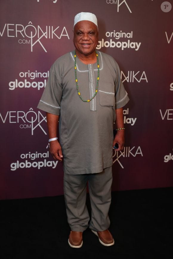 Ator marcou presença com uma túnica cinza de mangas curtas e gola entalhada com acabamento bordado, combinada a uma calça de corte reto da mesma cor e tecido. O figurino de inspiração afro-religiosa é arrematado por um colar longo de contas (guia) em tons de verde e amarelo e uma cobertura de cabeça (kele) branca. Nos pés, usa sapatos de couro marrom