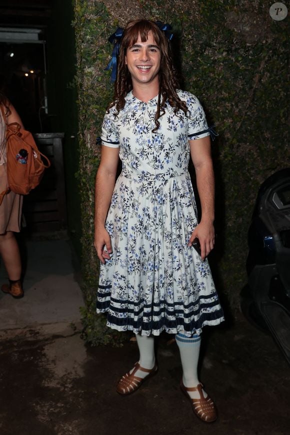 João Victor Gonçalves: incorporou a ingenuidade e o carisma de Bernadete (Chocolate com Pimenta)! Ele vestiu um delicado vestido floral vintage em tom branco e azul com gola redonda e mangas curtas, acompanhado de meias altas brancas e sandálias de couro marrom. Cabelos cacheados com laços azuis completaram o visual clássico e divertido do personagem