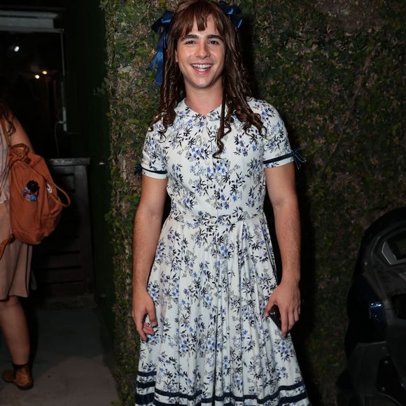 João Victor Gonçalves: incorporou a ingenuidade e o carisma de Bernadete (Chocolate com Pimenta)! Ele vestiu um delicado vestido floral vintage em tom branco e azul com gola redonda e mangas curtas, acompanhado de meias altas brancas e sandálias de couro marrom. Cabelos cacheados com laços azuis completaram o visual clássico e divertido do personagem