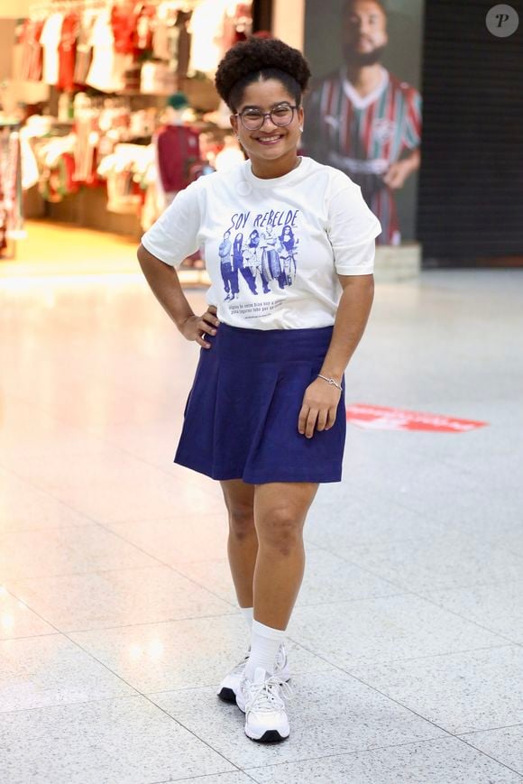 Tia Milena surge sorridente no aeroporto e rouba a cena com combinação fashion de saia plissada e tênis retrô