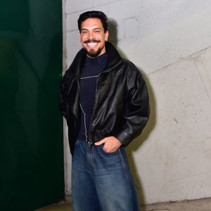 O ex-BBB Vinicius apostou na estética streetwear de inspiração noventista ao vestir uma jaqueta de couro preta em modelagem puffer. Por baixo, usou uma blusa azul-marinho de gola alta e combinou com calça jeans wide leg de lavagem azul-escura com recortes