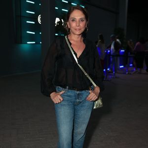 Heloísa Périssé investiu em um look casual chic impecável com uma camisa preta fluida de transparência suave e decote em V. A atriz combinou a peça com calça jeans reta de lavagem clássica e um tênis All Star de plataforma preto e branco. Os acessórios dourados, incluindo uma bolsa transversal metálica e argolas, deram o toque final