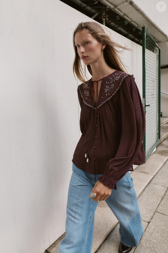 Blusa boho chic da Zara Brasil na cor marrom com mangas amplas traz autenticidade com detalhe artesanal dos bordados na gola da camisa, além das miçangas brancas presas no laço de mesmo tom da roupa.