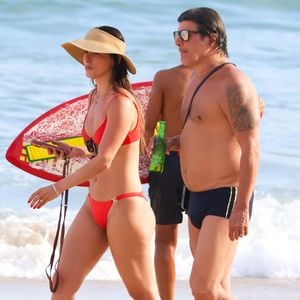 Para o passeio, Paulo Ricardo escolheu uma sunga preta com listras brancas, enquanto Isabella Pinheiro apostou em um biquíni vermelho com detalhes dourados