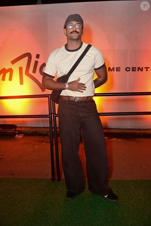 O ex-BBB Lucas Pizane escolheu uma camiseta de gola contrastante com calça marrom baggy, bolsa transversal e boné