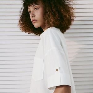 Em branco-marfim, a Camisa Crop em Mistura de Linho com Botões da Zara é confeccionada em mistura de linho e conta com mangas curtas, punhos com tira e fechamento frontal por botões