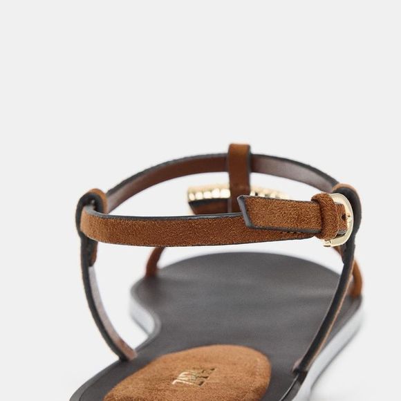 Com proposta versátil e elegante, essa rasteirinha aposta em uma tira frontal com aplicação metálica de concha como ponto de destaque. O modelo de  R$ 279,00 no site da Zara conta com fechamento no tornozelo por tira com fivela e acabamento em bico redondo, equilibrando simplicidade e sofisticação no dia a dia